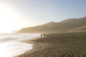 Scenic coastal landscape with rocky cliffs and ocean waves during golden hour.