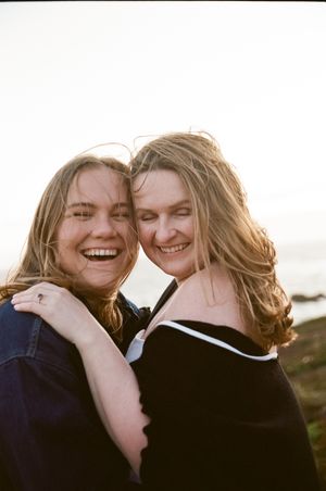 Candid joyful moment captured between two people with sunlit ocean background.