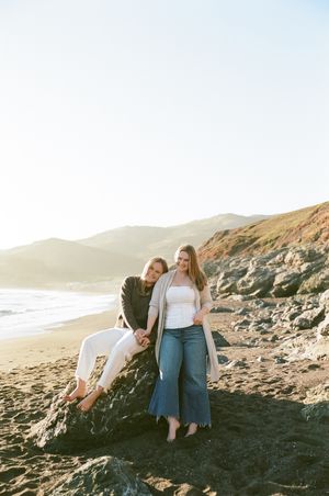 Friends enjoying a sunny day together on a rocky California coastline.