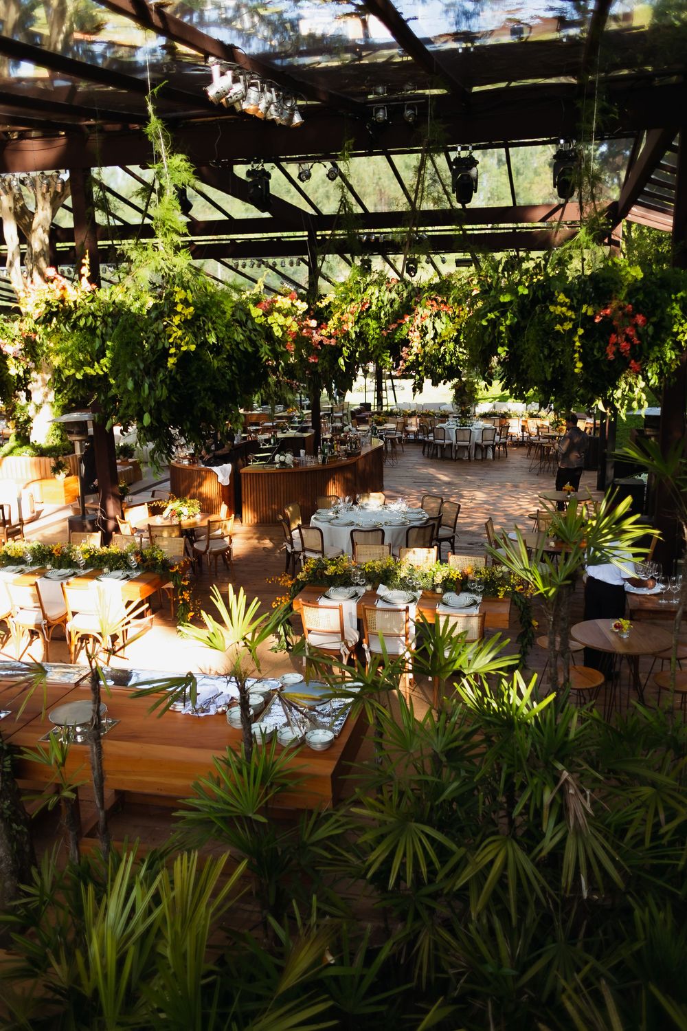 Lush tropical garden setting with dining tables arranged under a pergola for an outdoor restaurant experience.
