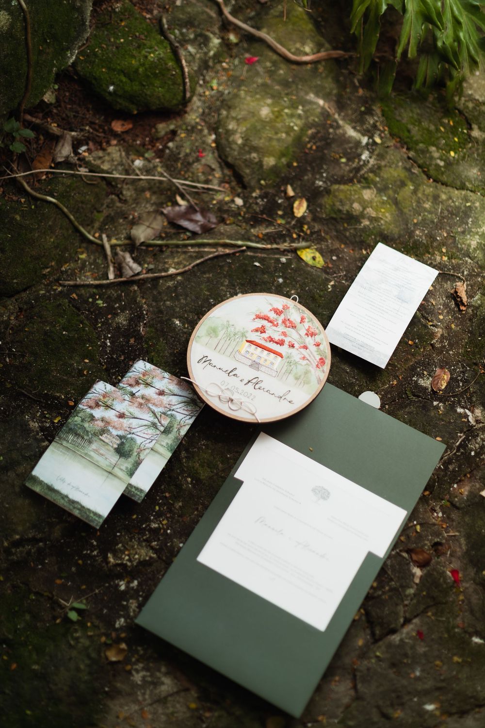 Wedding stationery and invitation cards arranged artistically on a dark stone surface outdoors.