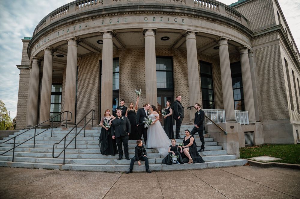 Wedding party gathered on grand stone steps of classical building with columns in Sandusky, Ohio.