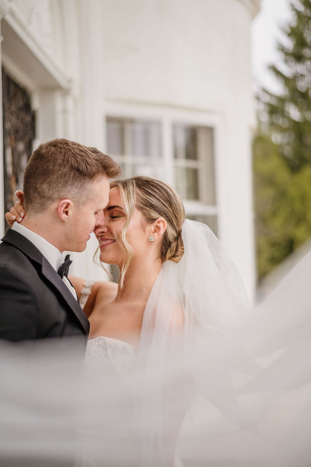 A tender moment captured between newlyweds through flowing white veil.