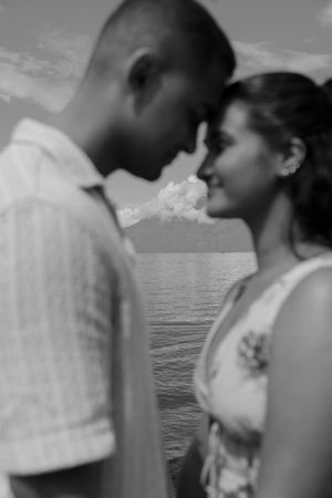 A romantic black and white photo series of a couple embracing by the ocean at sunset.