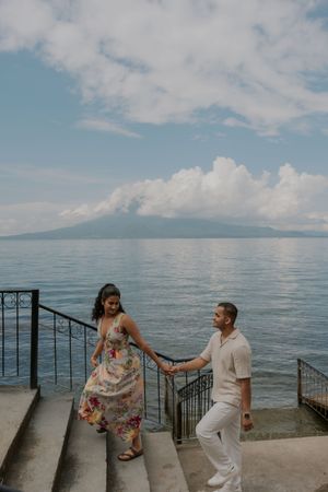 A couple shares a romantic moment on stone steps overlooking the ocean and mountains in Maui, Hawaii.