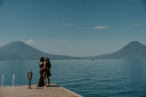 Scenic view of a wooden pier extending into calm blue waters with distant mountains under clear skies.