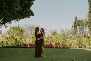 Couple embracing in a lush garden with colorful flowers and greenery.