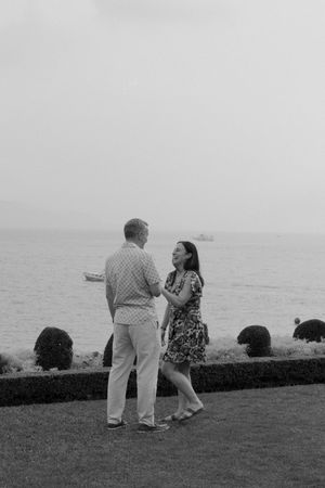 Black and white photo of a couple talking on a garden terrace overlooking the sea.