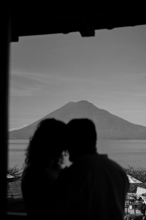 Silhouetted figures against a scenic mountain landscape at sunset create a romantic mood.