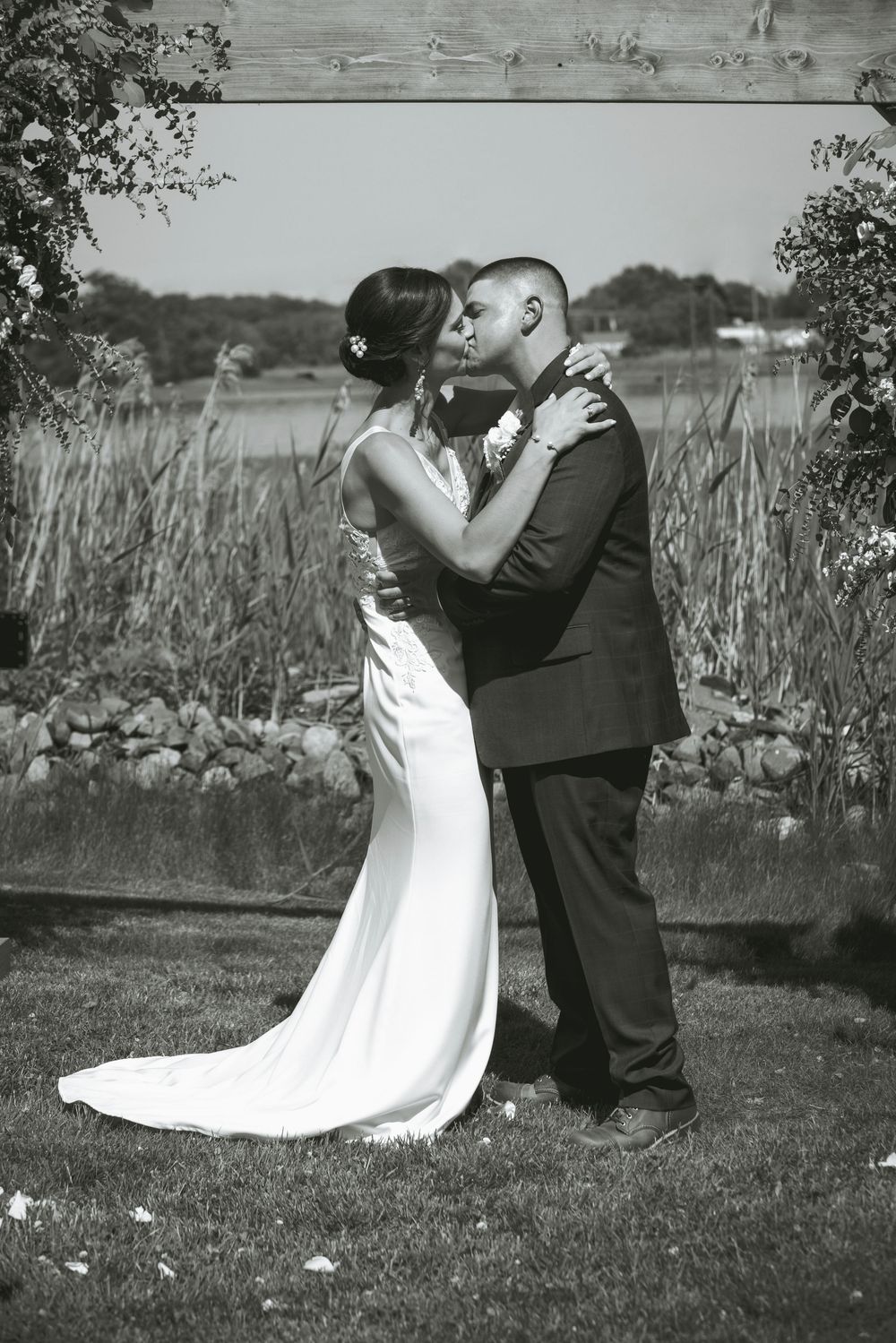 A black and white wedding portrait of a couple sharing an intimate moment outdoors.