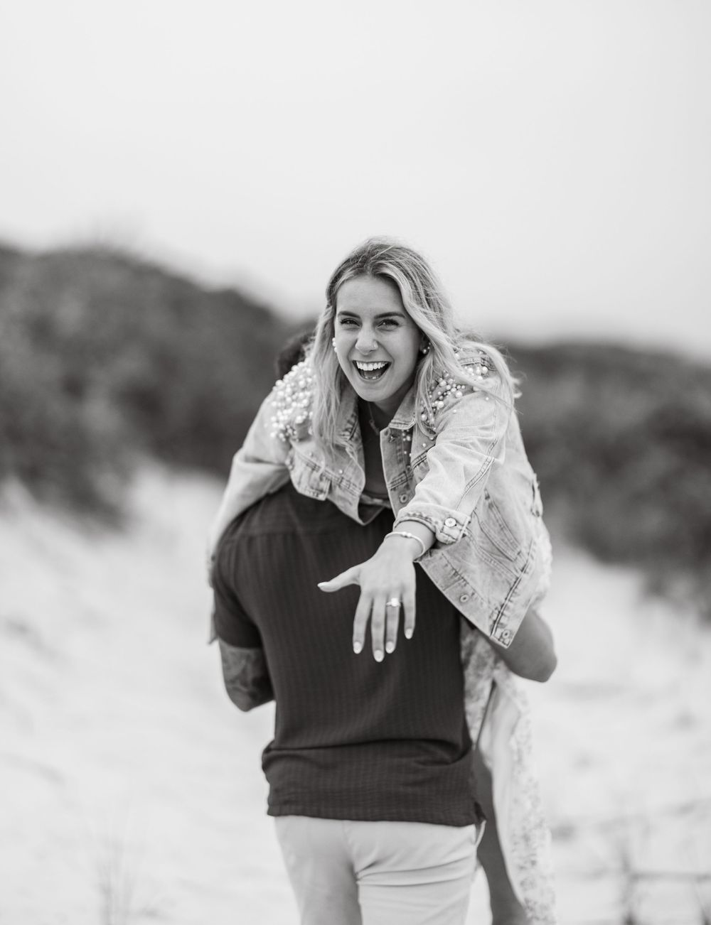 A joyful piggyback ride moment captured on the beach with natural lighting.