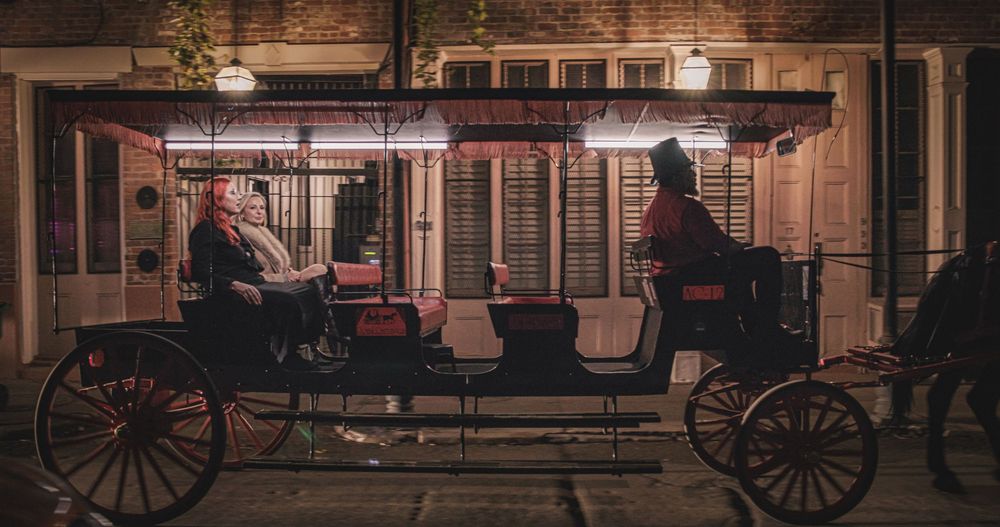 Horse-drawn carriages line a historic cobblestone street at night with warm glowing lights creating an atmospheric scene.