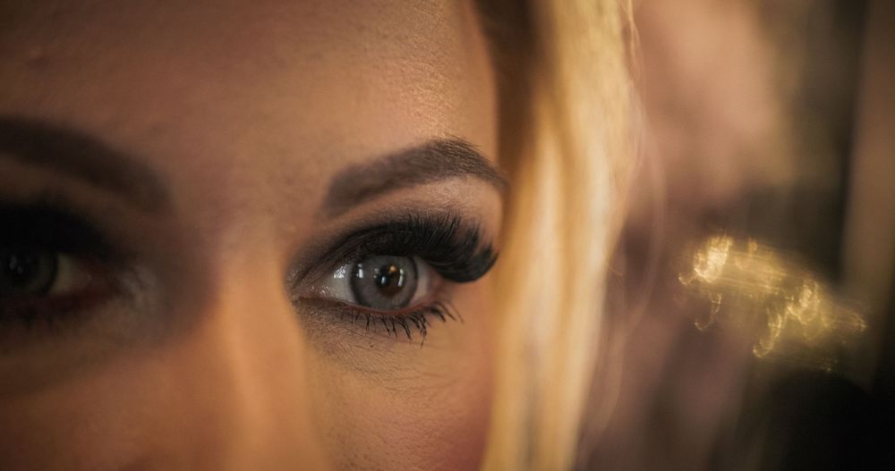 Close-up shot of eyes with dramatic false eyelashes and smokey eye makeup against a dark background.