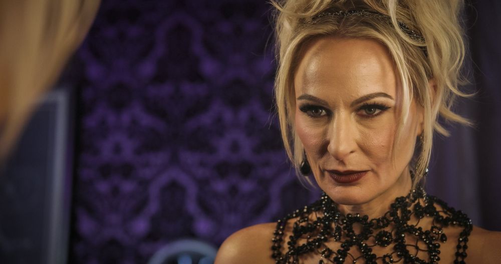 A glamorous evening look features black lace and delicate embellishments against a dark purple background.
