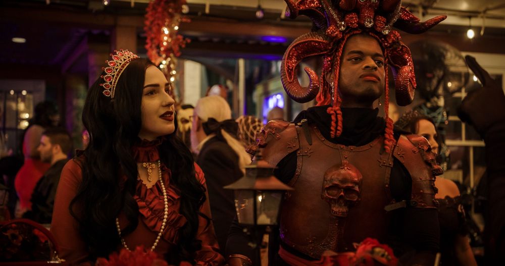Diverse crowd of people dancing and enjoying themselves at a lively nightclub party with red lighting.