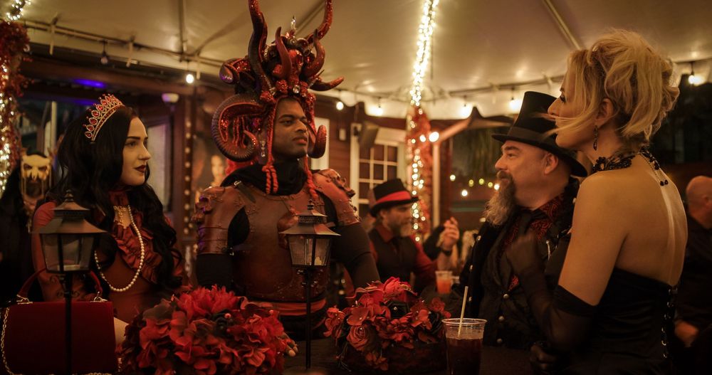 People enjoying drinks and socializing at a dimly lit bar with warm ambient lighting and festive decorations.