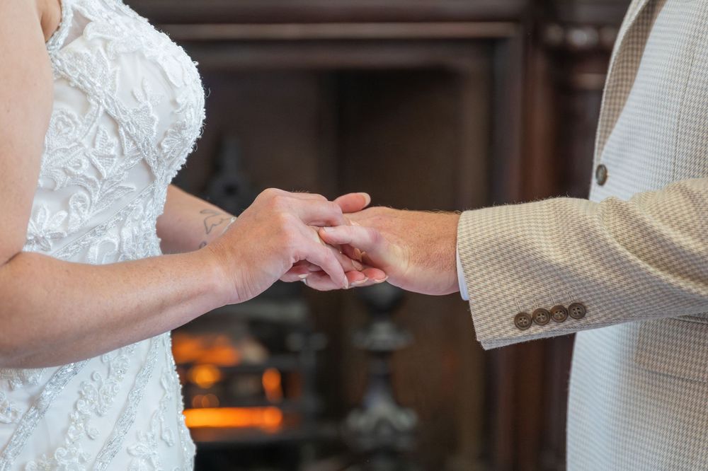 A couple holds hands during their wedding ceremony in a beautifully decorated indoor venue.