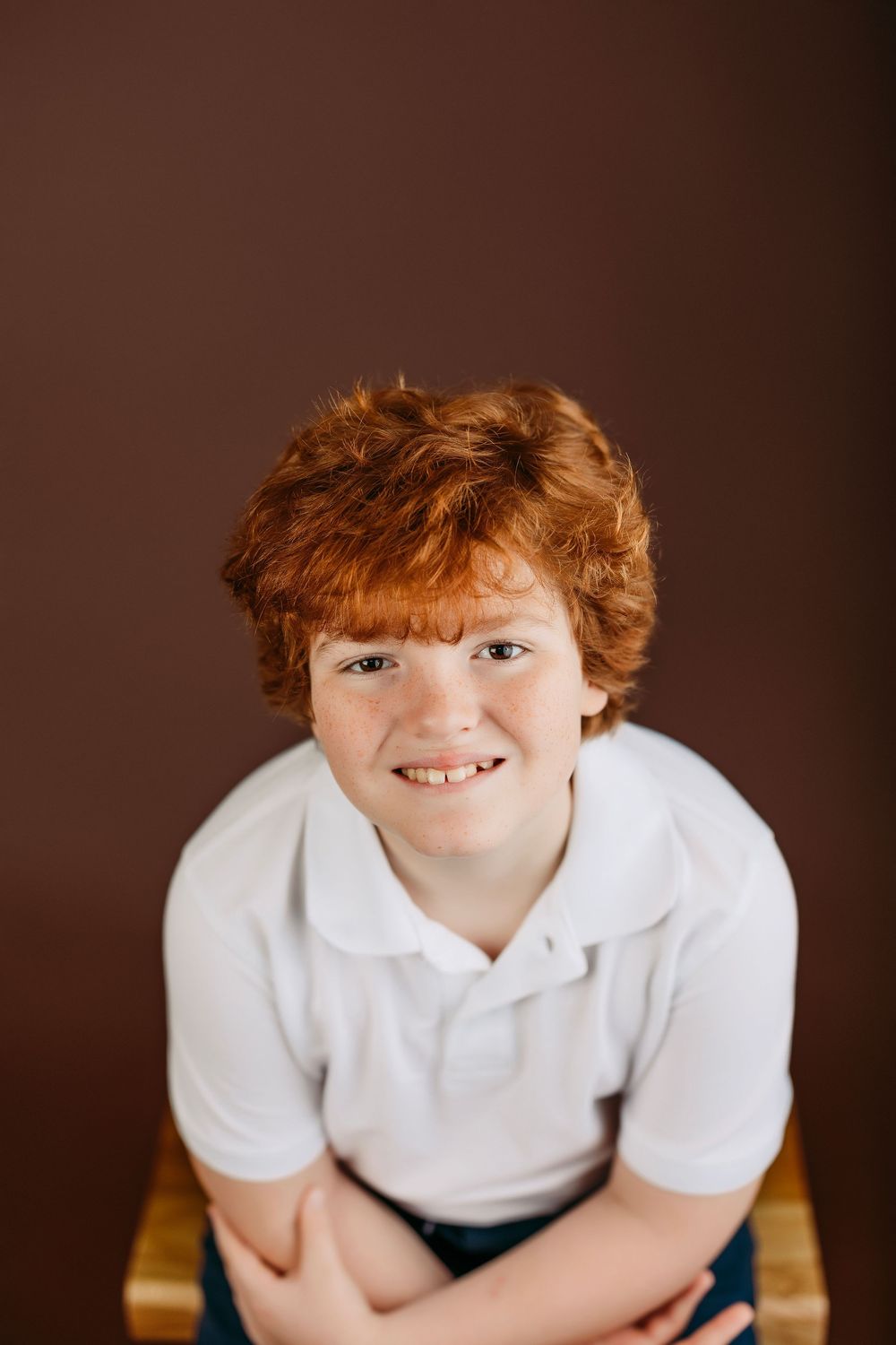 A sequence of four portrait photos showing someone in a white polo shirt against a dark brown background.