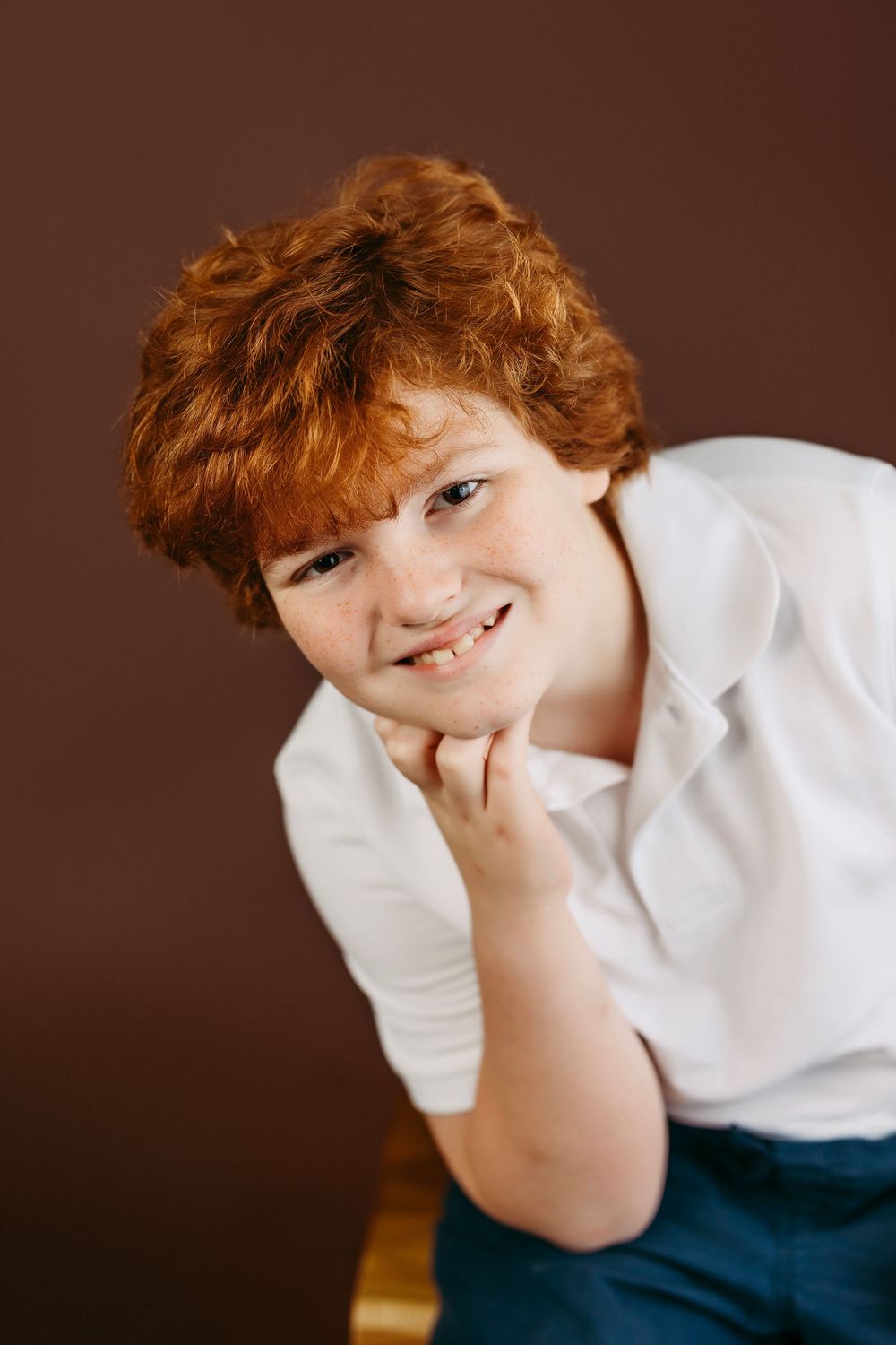 A series of candid studio portraits showing a young person with red hair in a white shirt against a brown backdrop.
