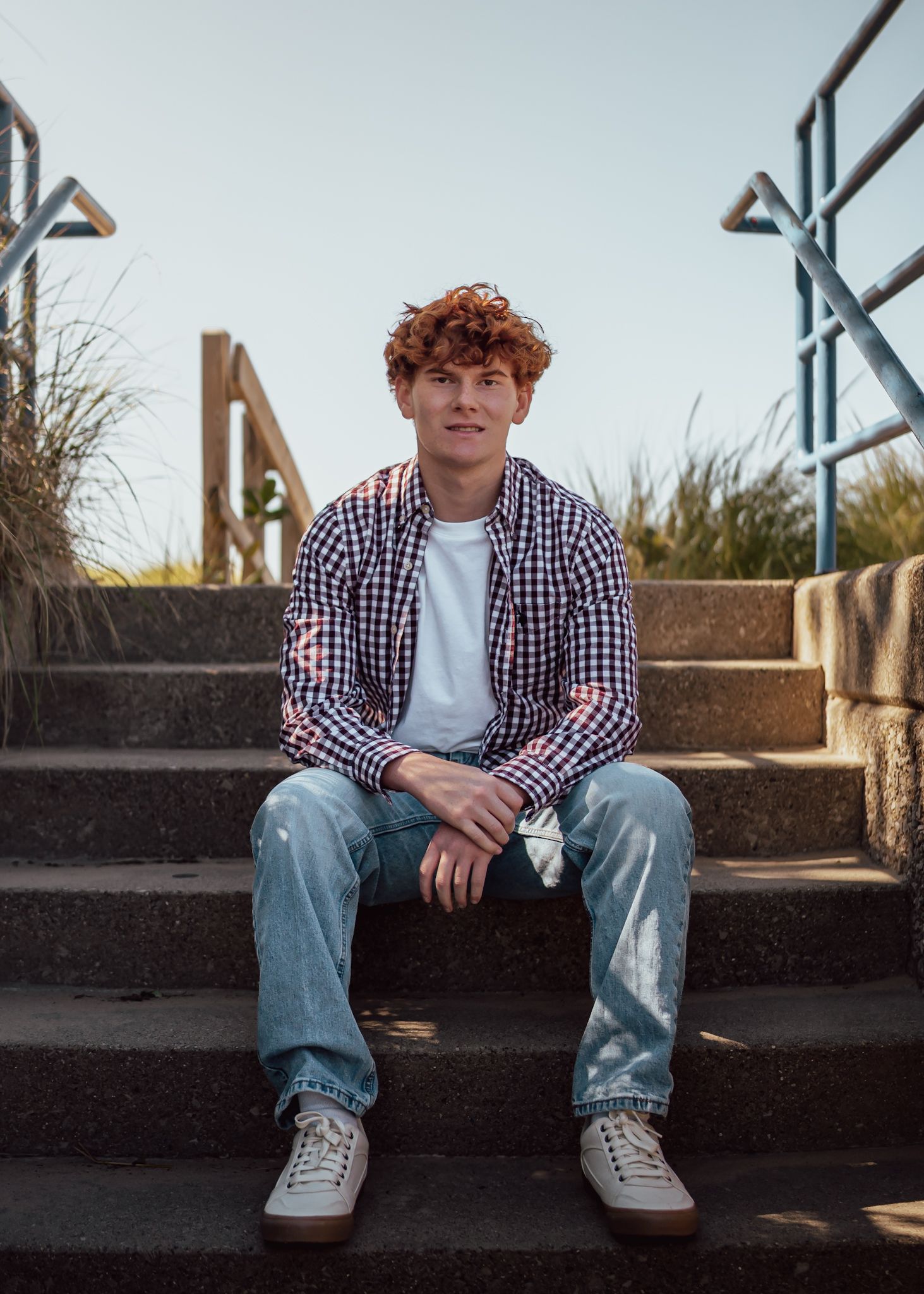 A casual portrait on concrete steps with natural lighting and architectural elements.