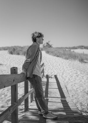 Black and white photo of a wooden boardwalk leading through sand dunes.