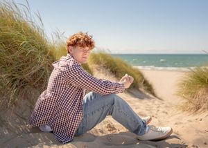 Scenic beach photography with sand dunes, ocean waves, and coastal vegetation.