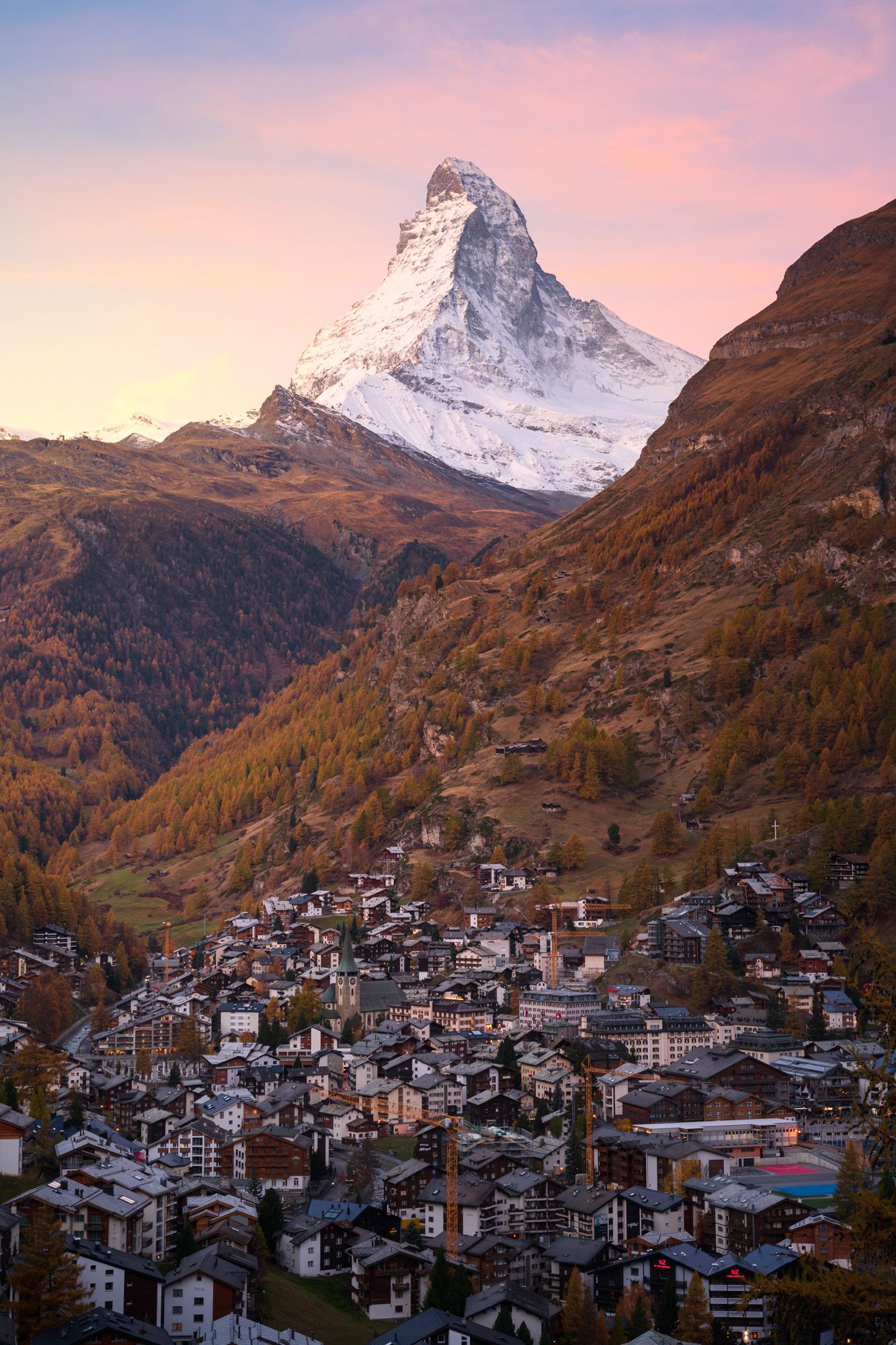 The Matterhorn peak towers over the village of Zermatt in Switzerland during a colorful sunset.