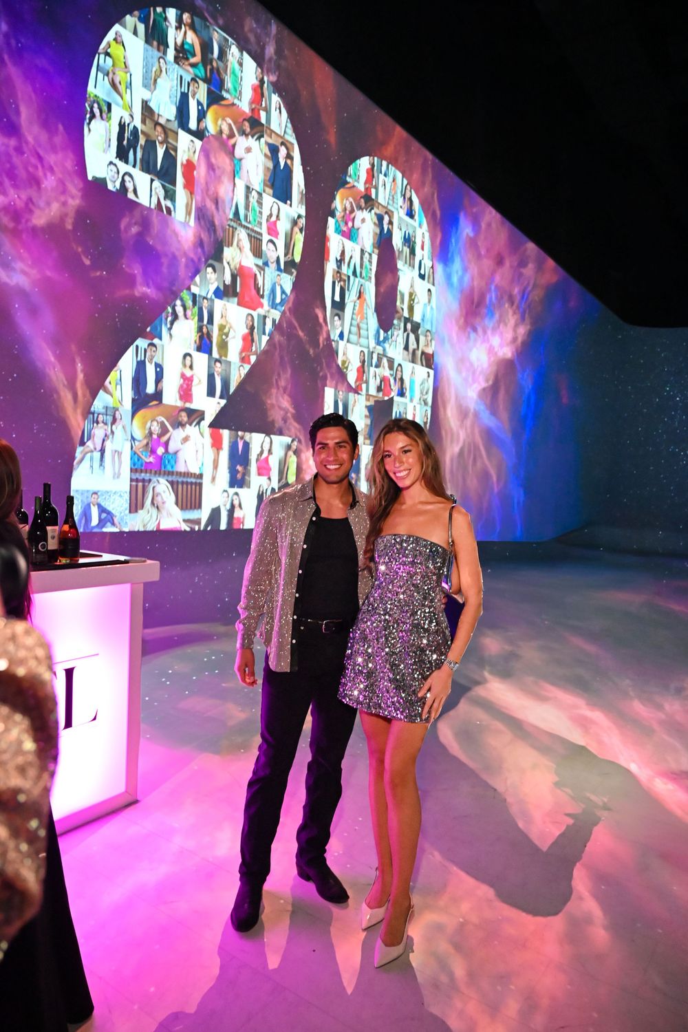 People dancing at a nightclub with vibrant pink lighting and video wall projections creating an immersive party atmosphere.