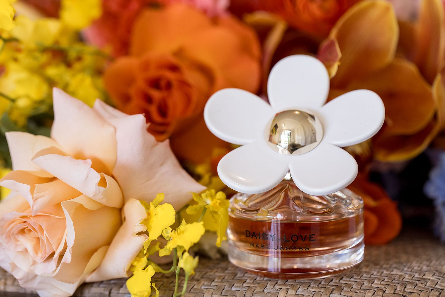 Delicate white orchids and peach roses arranged with yellow flowers on a rustic wooden surface with soft lighting.