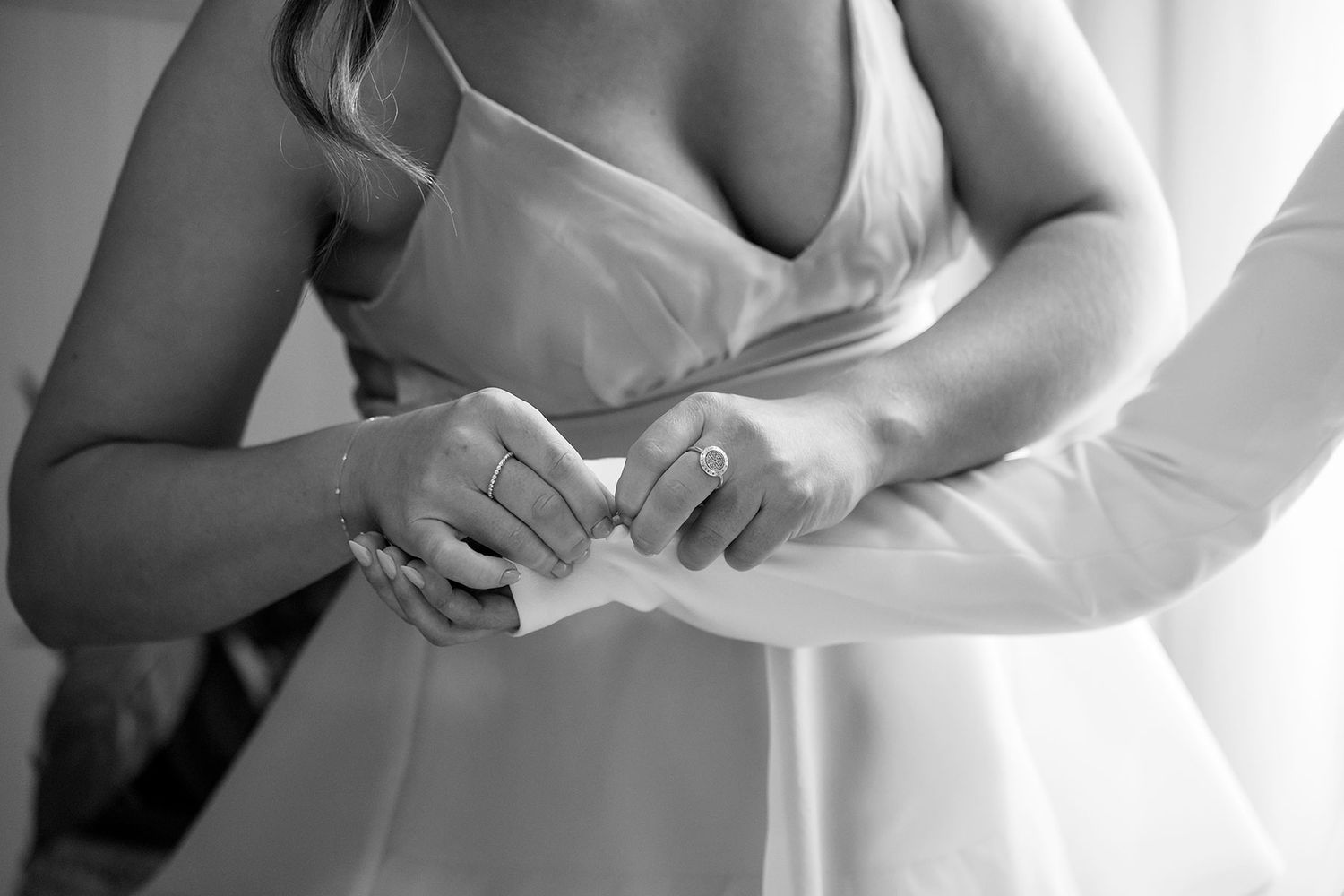 A close-up view of hands gently holding a delicate white wedding dress fabric.