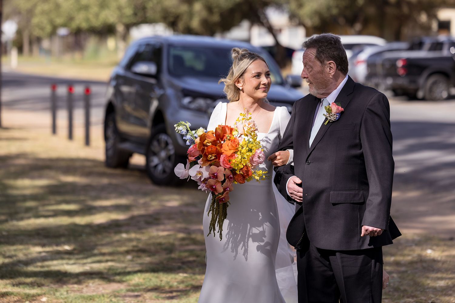 A bride walking arm in arm with her Dad into her wedding ceremony at the Balldale Hotel.