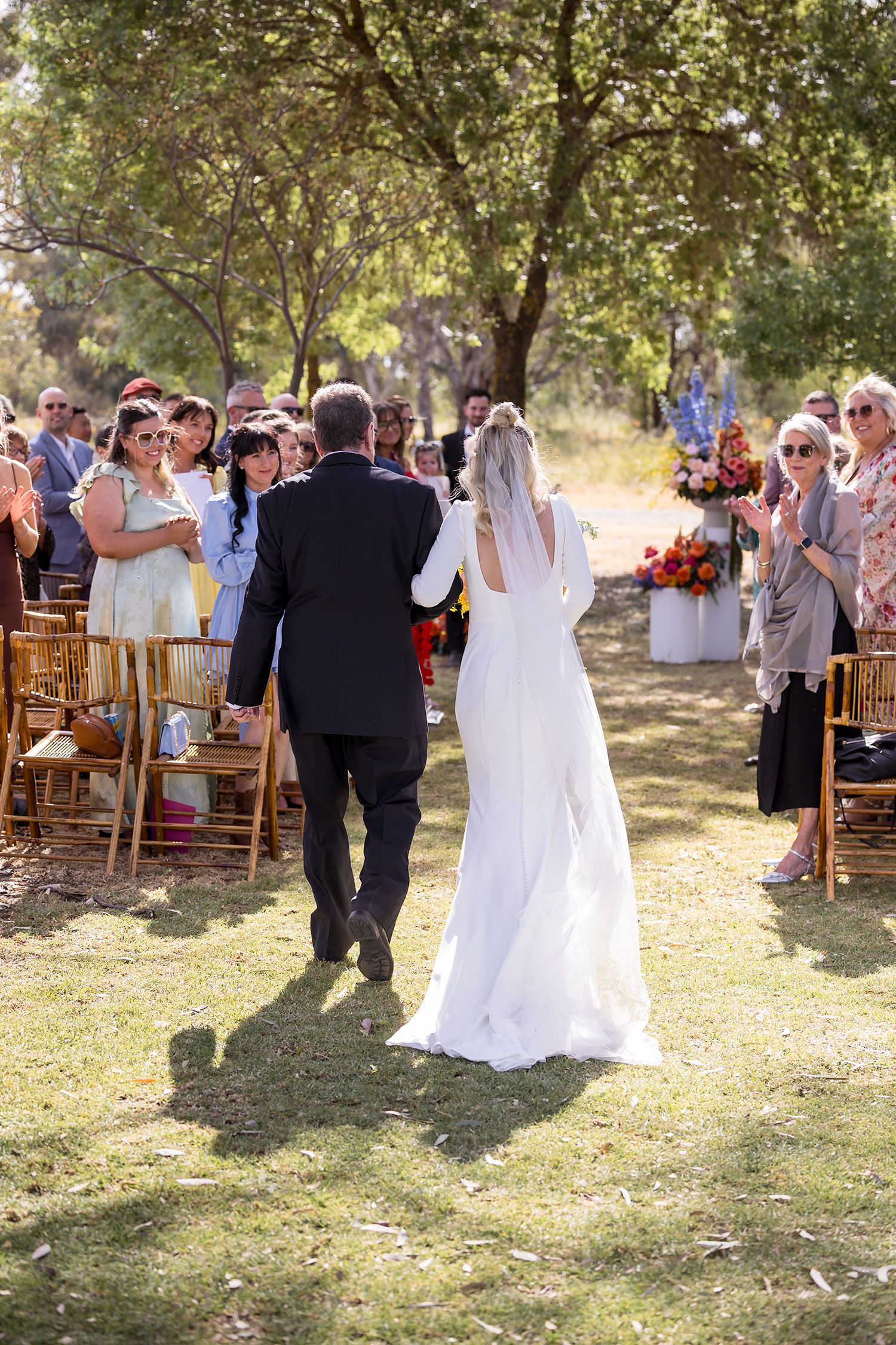 A bride walking arm in arm with her Dad into her wedding ceremony at the Balldale Hotel.