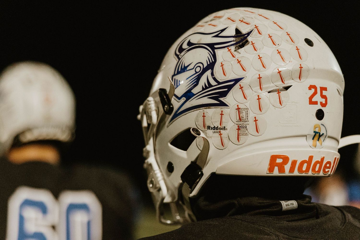 Denver Broncos football helmets lined up on display showing white protective gear with orange accents and team logos.