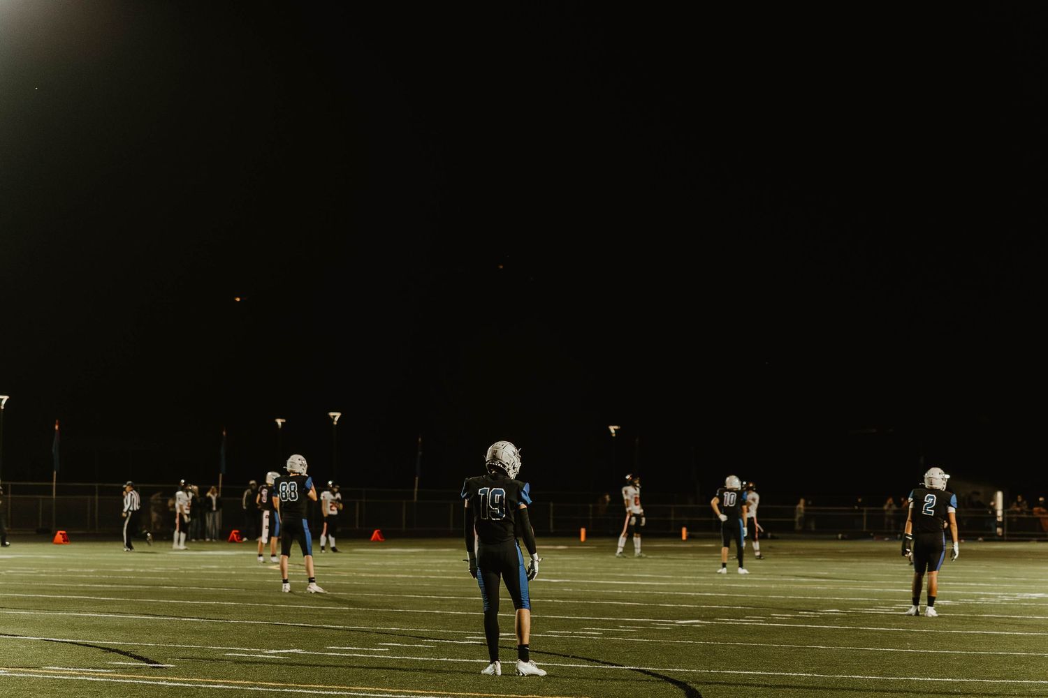 Athletes playing on a sports field at night under bright stadium lights during a competitive match.