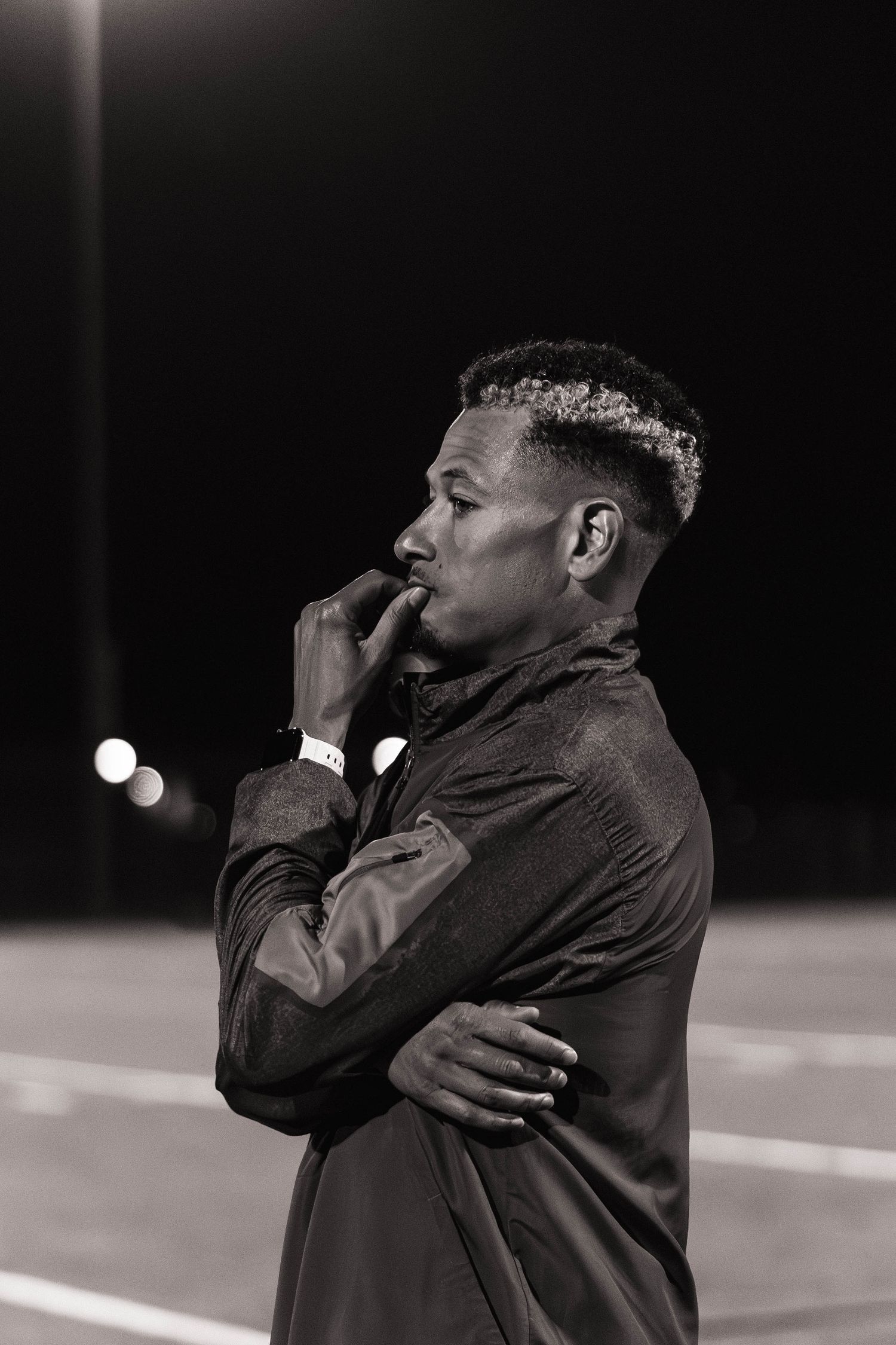 Black and white sequence of a person in a dark jacket making dramatic gestures against a dark background.