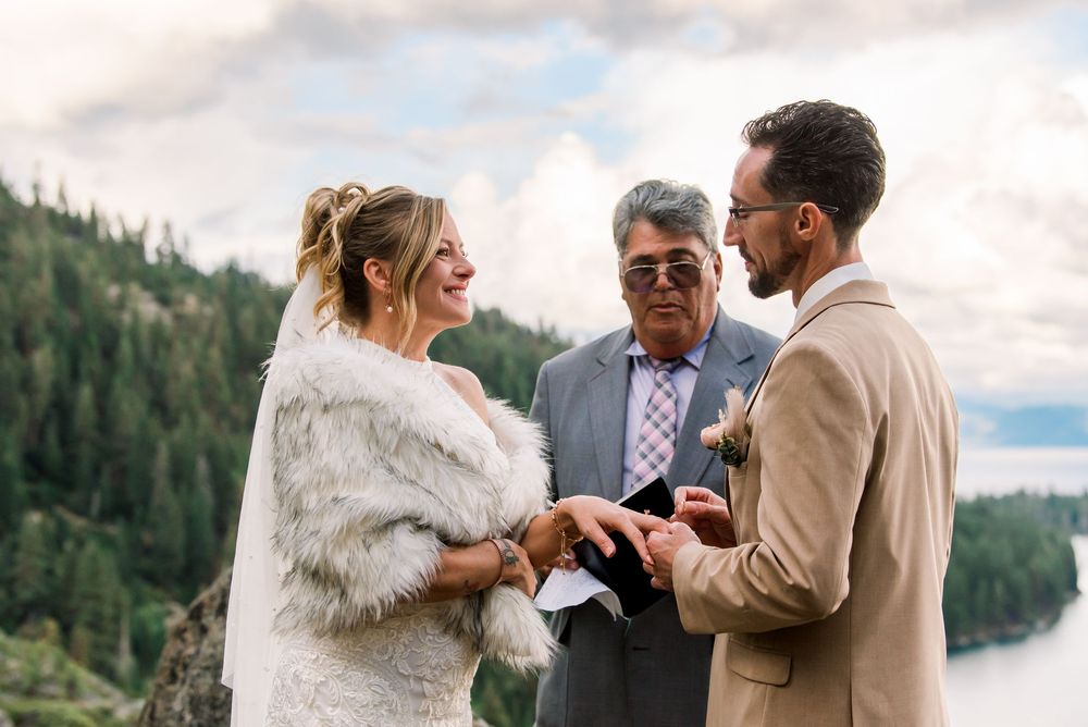 A couple exchanges rings during an outdoor ceremony with an officiant present.  A Destination Wedding at Emerald Bay State Park. Lake Tahoe.