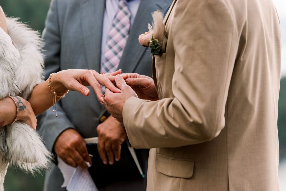 A couple in wedding attire share a romantic moment during their outdoor ceremony.