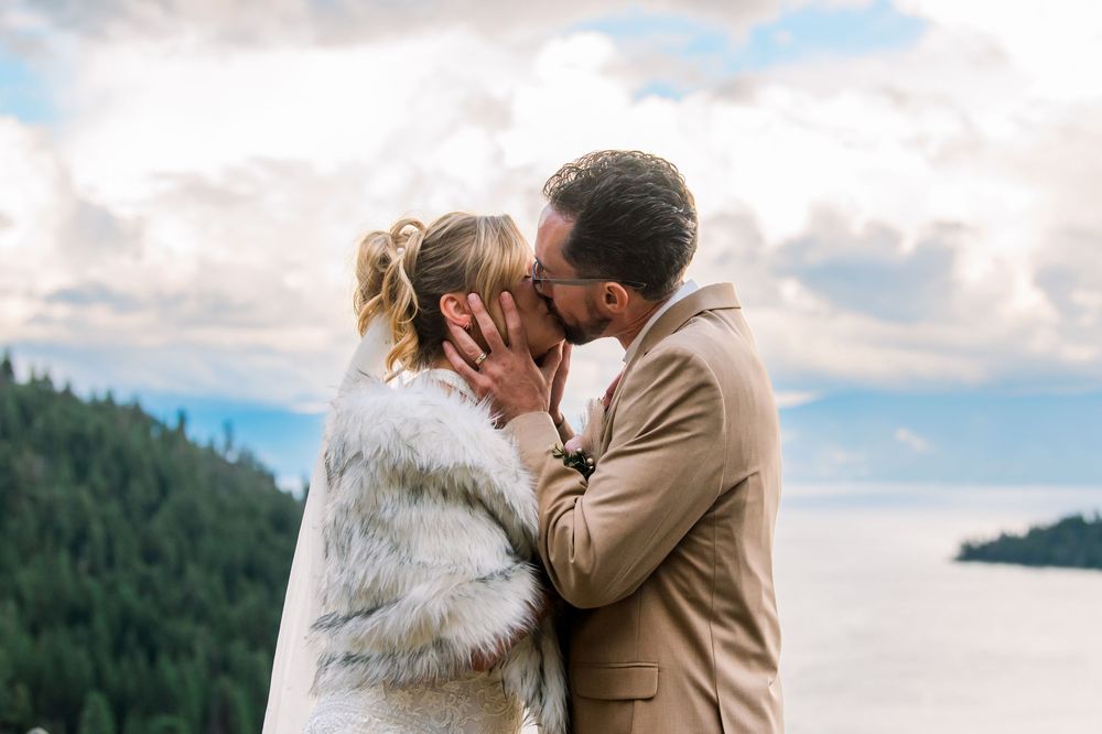 A romantic wedding couple shares intimate moments in front of a scenic mountain landscape during golden hour.