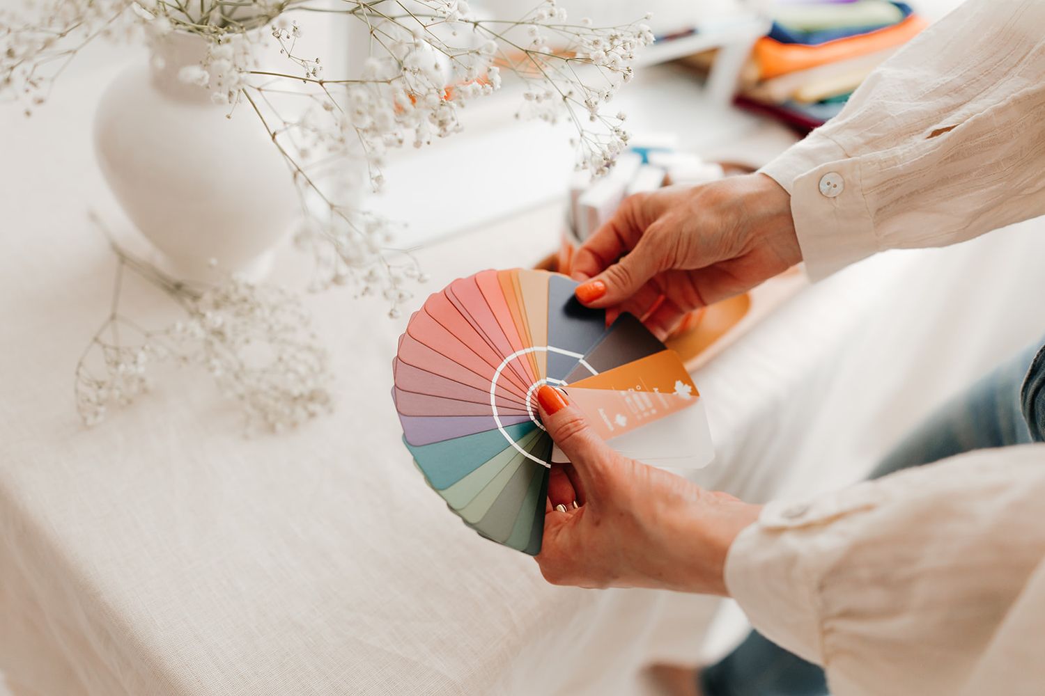 Close-up of hands holding paper fans with delicate baby's breath flowers in the background.