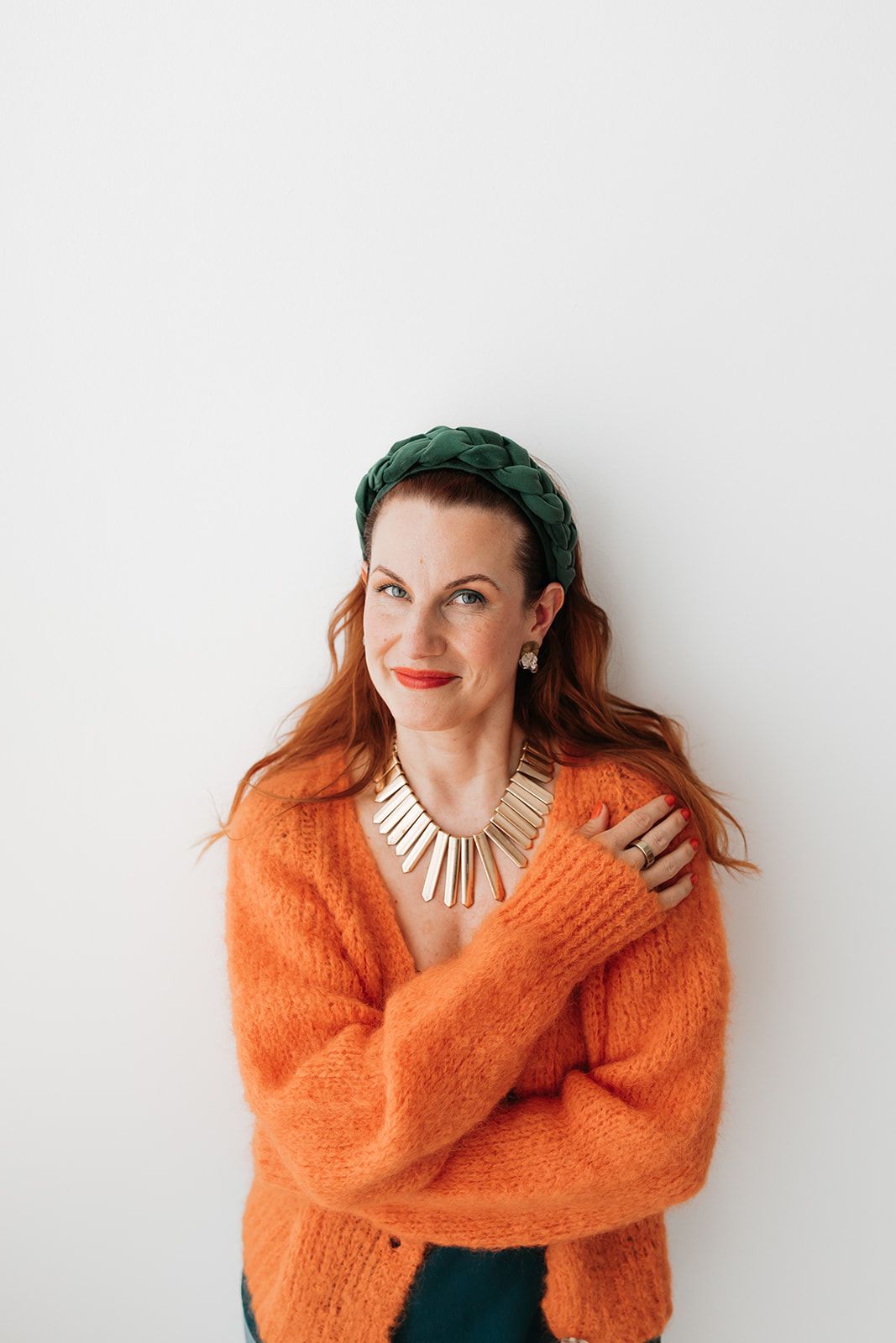 Person in bright orange sweater and green beret poses playfully against white background in multiple shots.