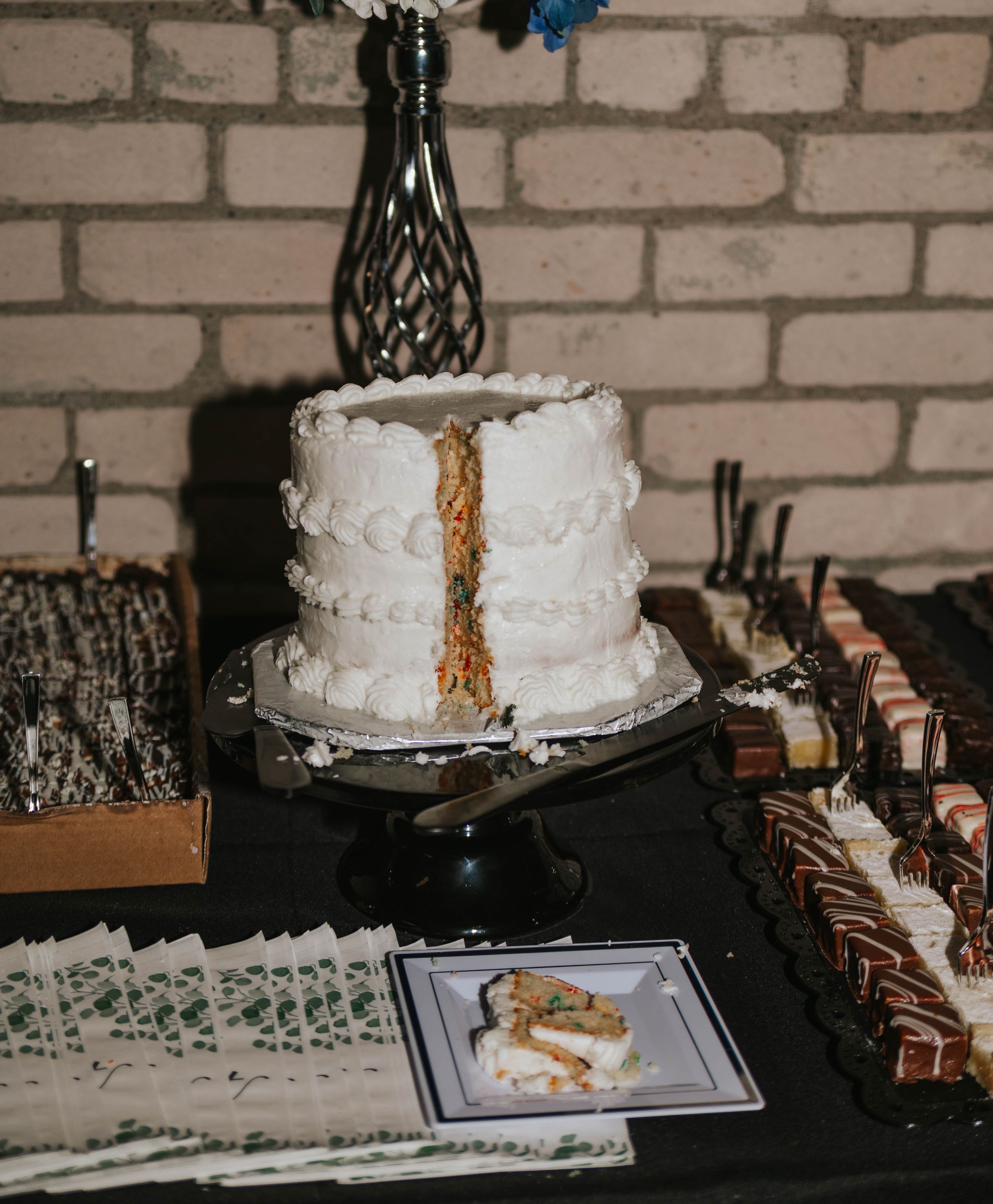 A white frosted cake with a golden drip effect shown in a sequence of images on a dark surface against a brick wall.