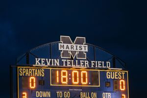 Illuminated football stadium scoreboard at night showing Kevin Teller Field with time and score display.
