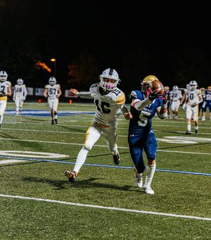 Football players from opposing teams face off on field during night game.