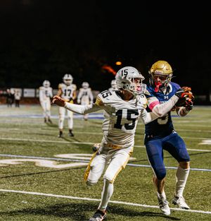 Football players engage in intense defensive action during a night game on an illuminated field.