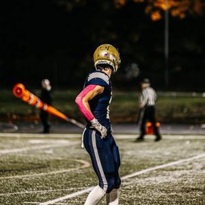 Football player in navy uniform makes a play on a snowy field during a winter game.