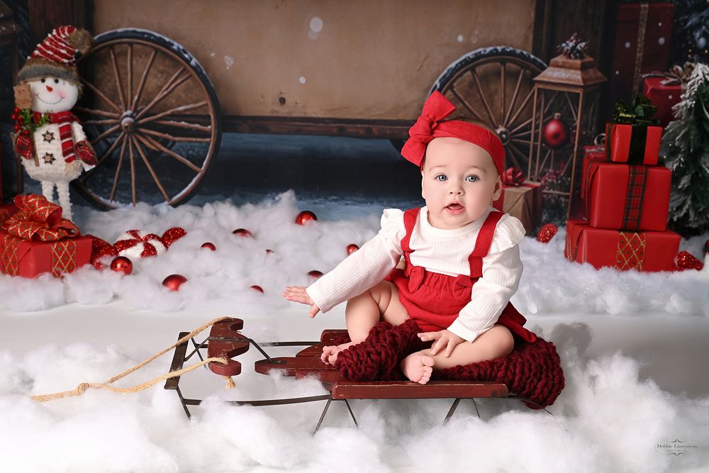 Holiday photo session in a festive red and white Christmas setting with decorative snowmen and winter decor.