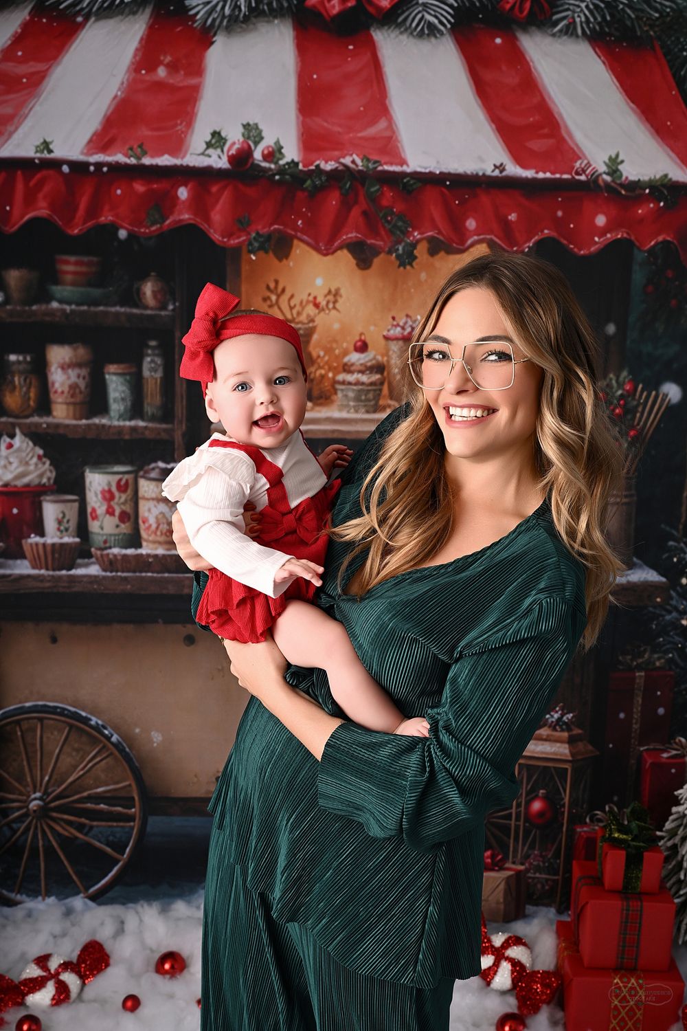Candid holiday photoshoot in front of a Christmas-themed backdrop with red and green decorations.