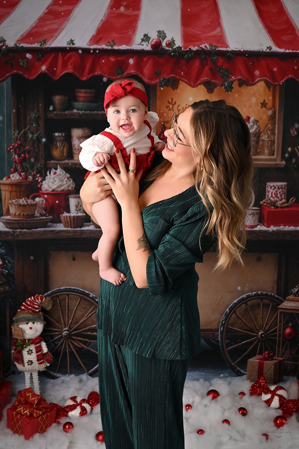 Festive Christmas photo session with red and white striped awning and vintage holiday decor.