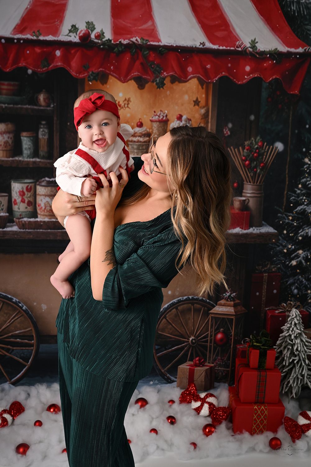 Sweet holiday photo session featuring a parent and baby against a Christmas themed background.