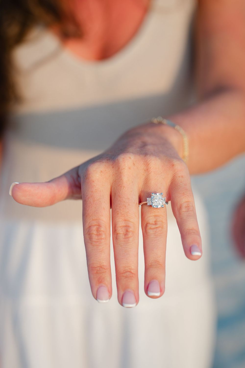 Close-up view of an engagement ring on a woman's hand with a sparkling diamond solitaire.